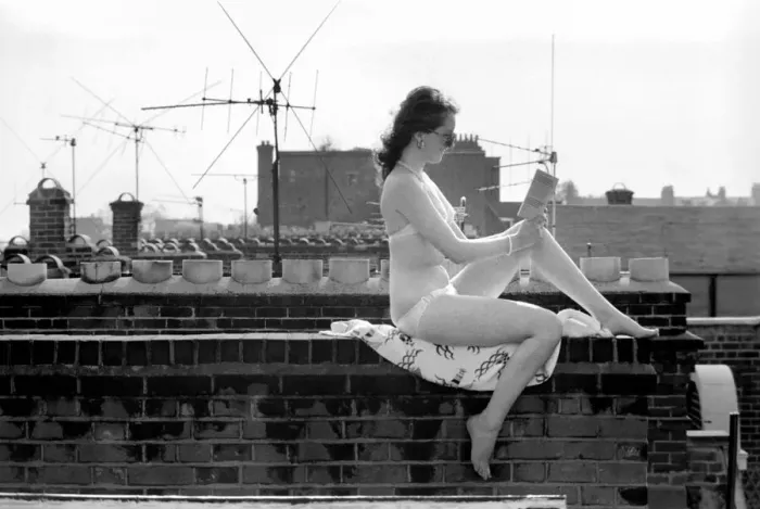 Framed Print : A model wearing a bikini reading a book as she sunbathes on a rooftop on Kings Road in