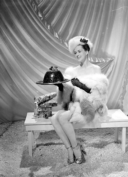 A model wearing fur hat wrap and glove holding a christmas pudding
