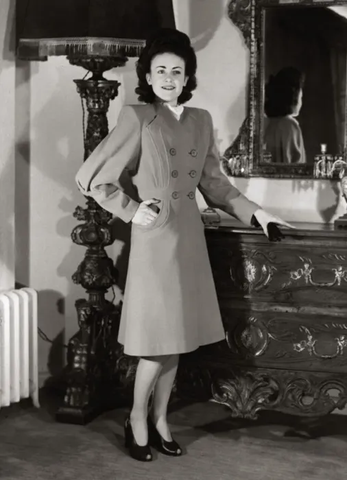 Framed Print : A model wearing a harella coat with new shaped sleeves and flared skirt standing beside a Framed Print : A model wearing a harella coat with new shaped sleeves and flared skirt standing beside a
