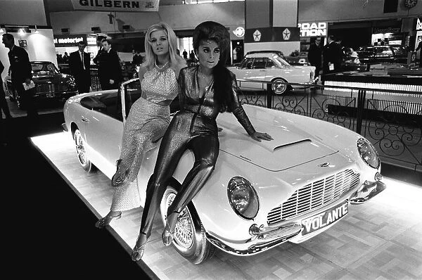 Models pose on the bonnet of a Aston Martin Volante at Motor Show 18th October 1966