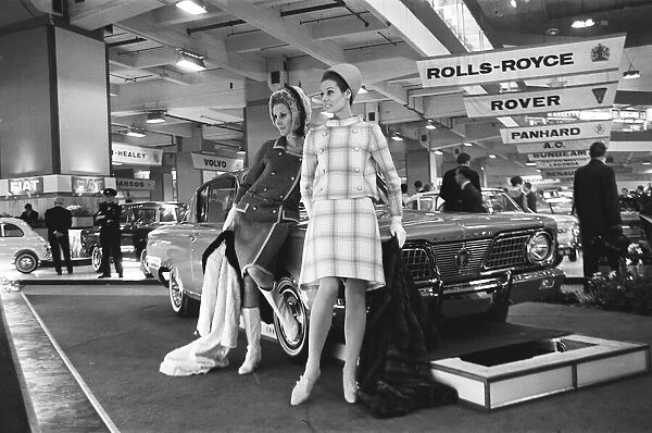 Models pose by the bonnet of a Plymouth car at the British International Motor Show in