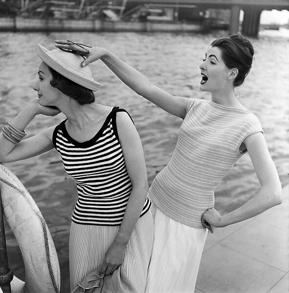 Models by a river, one is wearing a striped cotton sweater. 14th June 1957