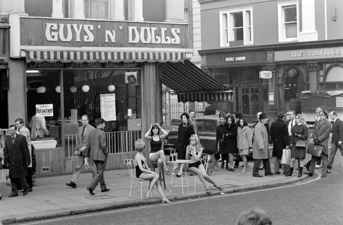Framed Print : Models wearing swimsuits sit outside Guys and Dolls in the Kings Road Chelsea London Framed Print : Models wearing swimsuits sit outside Guys and Dolls in the Kings Road Chelsea London