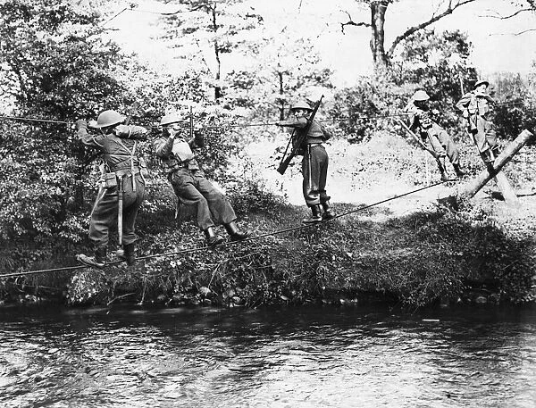 Monmouthshire Home Guard negotisting a river by means of a slender wire bridge of their