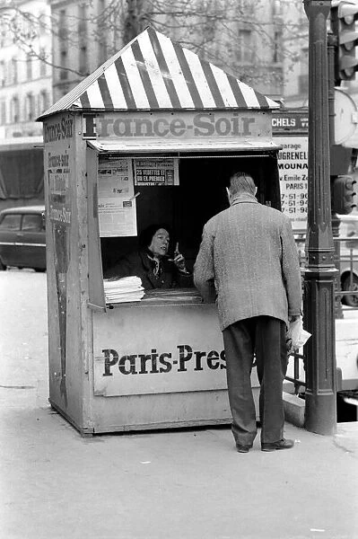 A Morning newspaper reader picks up his paper from a kiosk in the 15th district of Paris