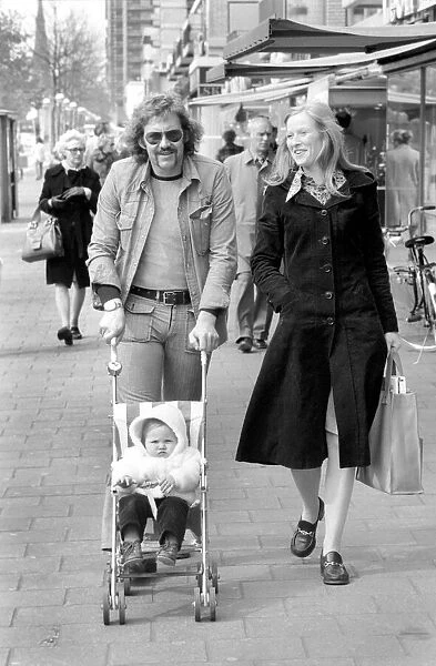 Mother and father pushing their little daughter along in a bugg on the streets of