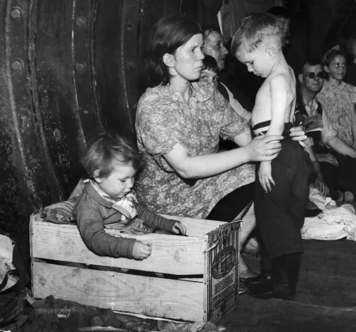 Framed Print : A mother tends to her young son while her daughter settles into a bed made from a wooden