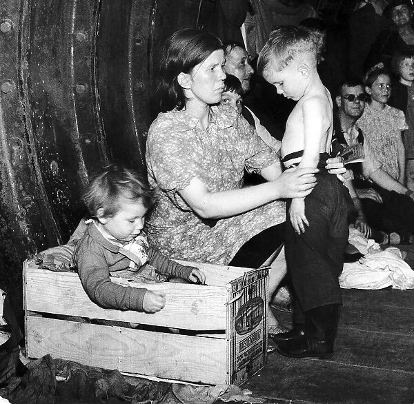 A mother tends to her young son in an underground bomb shelter during an air raid while