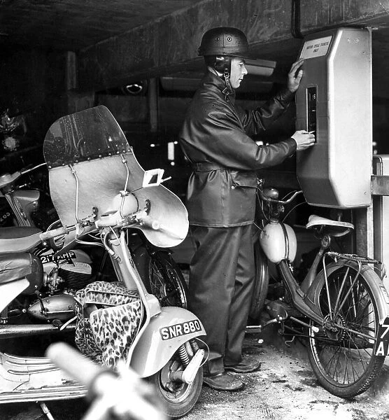 A motor cyclist puts his sixpence in the ticket machine in the new motor cycle '