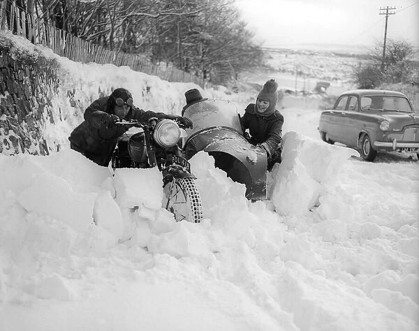 Two motor cyclists try to push through giant snow drifts in Devon but find the roads
