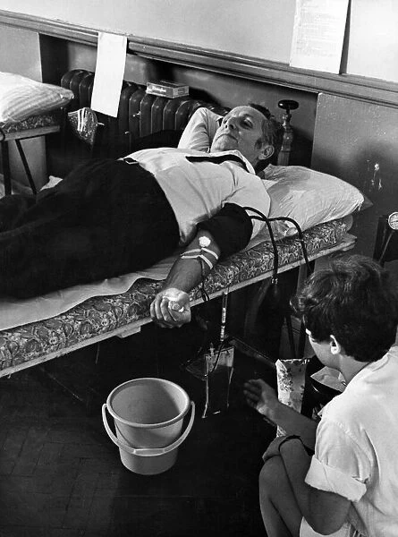 Mr Leo Abse, MP, giving a pint of blood at the South Wales Branch of the Medical Aid for