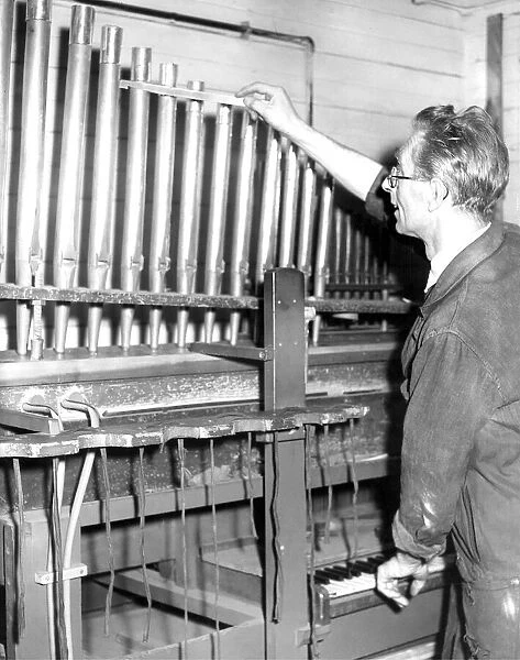 Mr. Leslie Rowland, aged 53, tunes the pipes of this organ on a voicing machine in