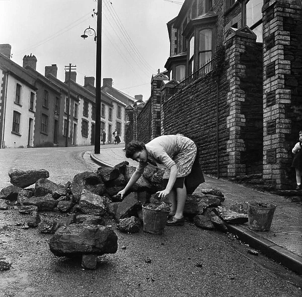 Mrs Annie Berry takes in her coal, which is delivered in a heap in the street
