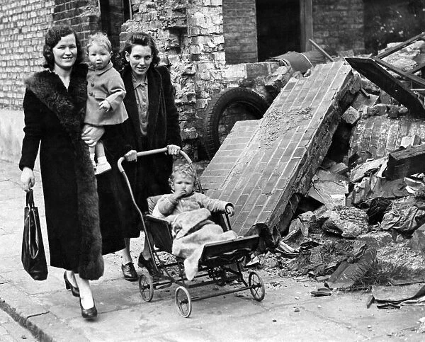 Mrs Applegate (left) and Mrs King with children, walking past a bombed building