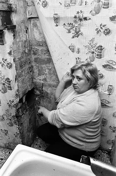 Mrs Mary Wall points out peeling wallpaper and hole in brickwork which she claims was