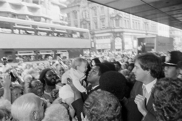 Muhammad Ali holds up a baby on his visit to Birmingham. 9th August 1983