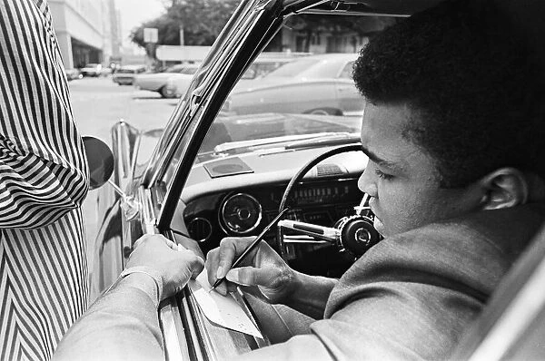 Muhammad Ali signing an autograph for a fan. 31st August 1967