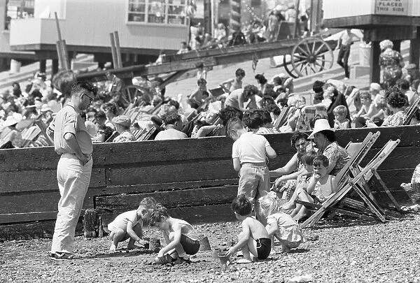 Mum enjoys a sandwich and dad looks on as children build sand castles on the beach at