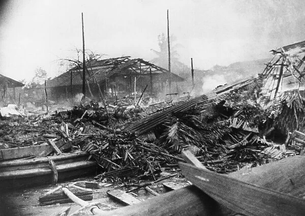 Native houses are reduced to smouldering ruins after the Japanese bombers have passed