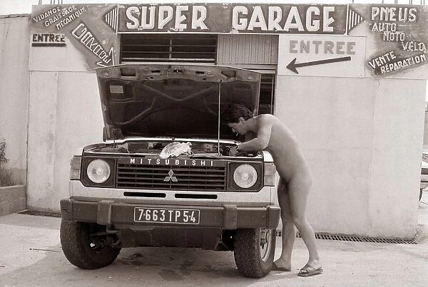 Naturist Nudist Village - July 1987 naked man working on a vehicle in the garage
