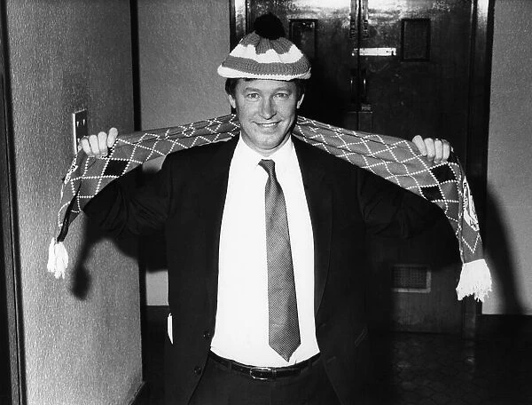New Manchester United manager Alex Ferguson proudly shows off the team hat