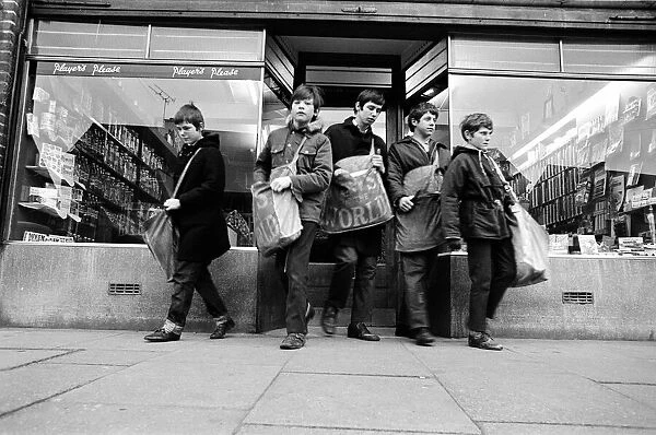 Newspaper round boys leaving the newsagents with their newspapers, ready for delivery