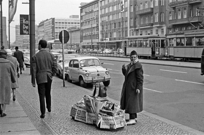 Framed Print : Newspaper vendor on the Kufurstendamm, Berlin, keeps herself warm with a cup of coffee