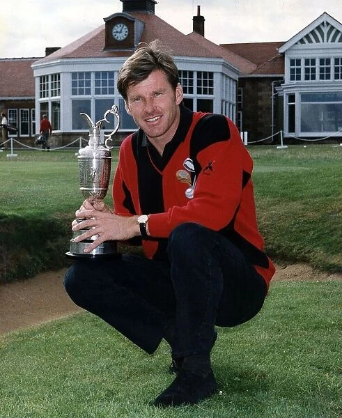Nick Faldo crouching holding the British Golf Open trophy