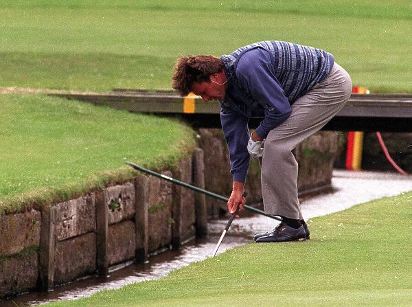 Nick Faldo retrieves his ball from the Swilken burn at the 1st after putting his ball in