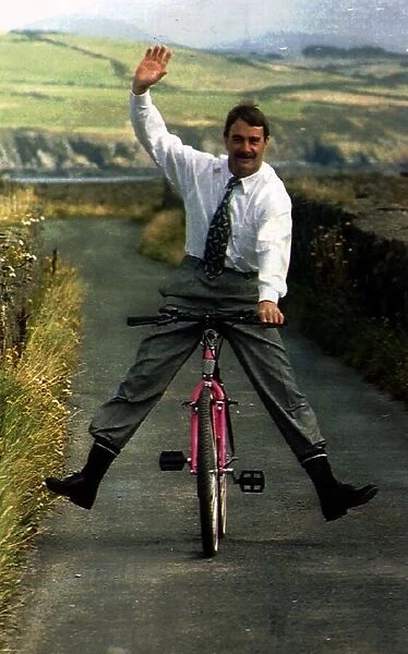 Nigel Mansell Formula One Racing Driver Riding A Bicycle Down A Country Lane