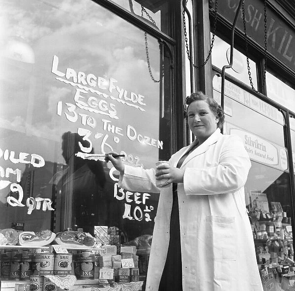 Norma Watson, manageress of a grocery shop in Sale, near Manchester repaints the egg sign