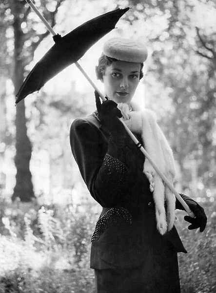Norman Hartnell fashions. A woman holding a brolly in black velvet gloves