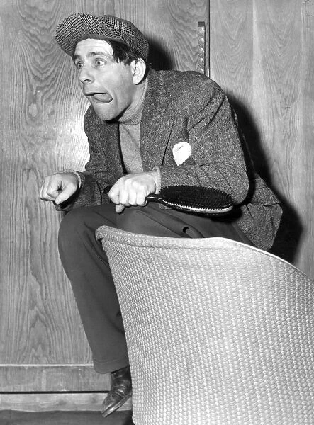 NORMAN WISDOM ACTS AS A JOCKEY ON HIS DRESSING ROOM SEAT, LONDON PALLADIUM - MAY 1954