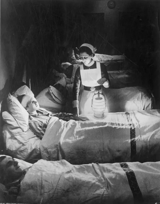 Framed Print : A nurse holiding a lamp as she visits patients on a ward at Westminster hospital