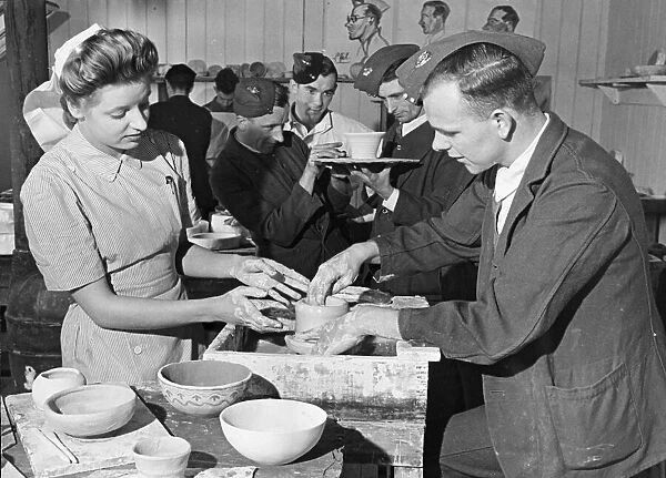 Nurse Pat Tait instructs wounded troops in curative pottery at a workshop for injured