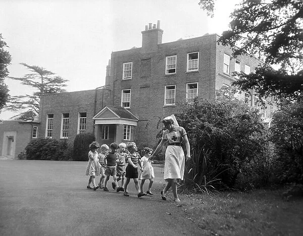 A nurse takes some children for a walk around the grounds of the Beech Hill Convalescent