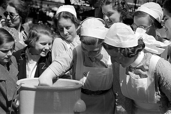 Nurses dunk their hands into a bucket at Barts Fair circa 1938