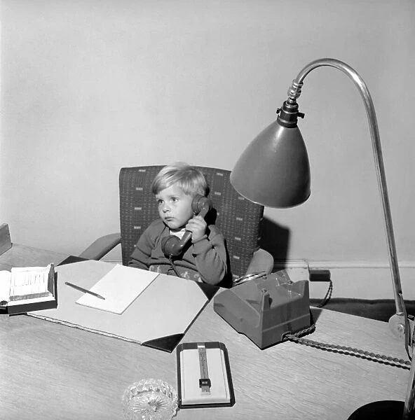 Office Junior: Two year old boy helps out at the offices of Theobald and son. 1957