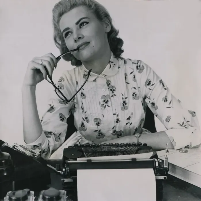 Framed Print : Office worker at typewriter chewing the end of her glasses July 1958 Framed Print : Office worker at typewriter chewing the end of her glasses July 1958