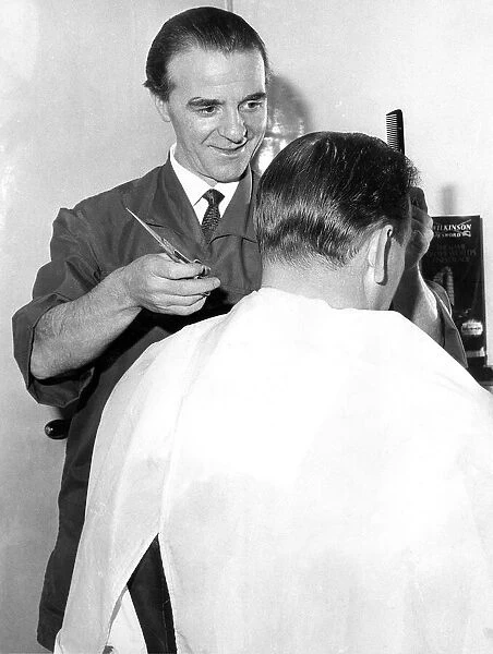 An old fashioned barber cutting a mans hair in February 1966