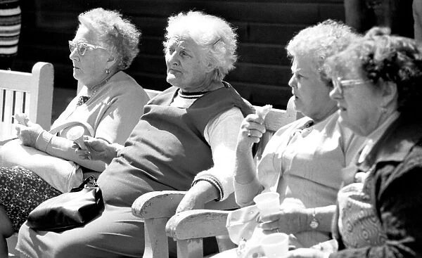Old ladies sitting on a bench eating ice cream during a day out to the beach at Trecco
