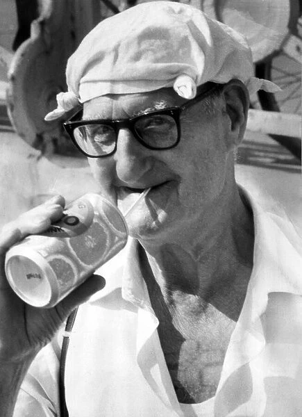 Old man on beach enjoying a drink in the heat. 21st August 1981
