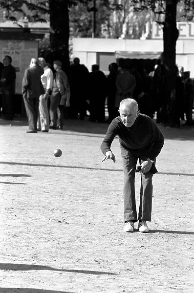 An old man playing a game of boules in a street in Paris, France
