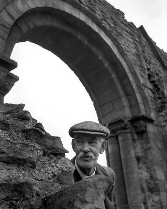 Framed Print : An old man wearing a flatcap peeping out from underneath an archway Framed Print : An old man wearing a flatcap peeping out from underneath an archway