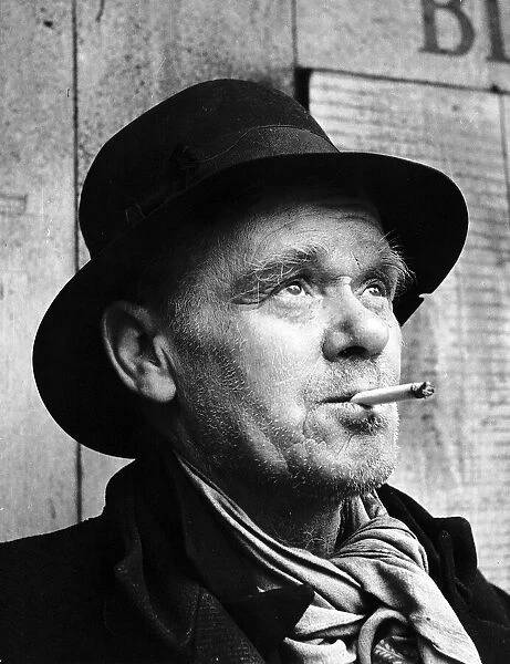 Old man wearing hat smoking cigarette June 1946
