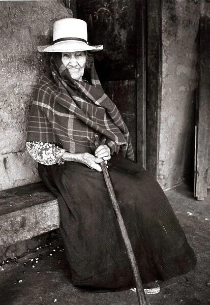 Old Woman sitting on a bench with a cane circa 1930