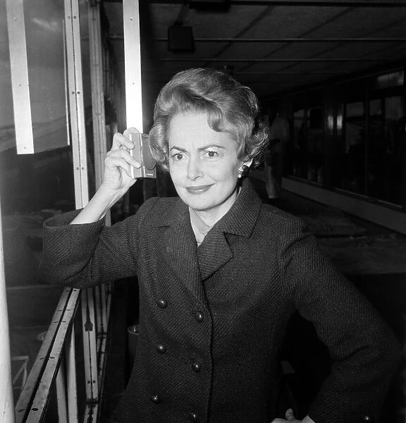 Olivia De Havilland listens to the budget at London Airport while waiting for a flight