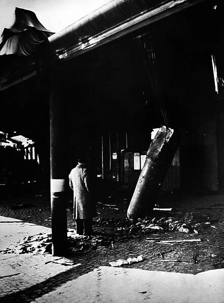 An onlooker examines an unexploded aerial mine comes to rest outside a railway station at
