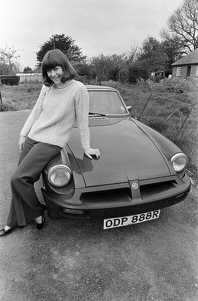Pam Ayres poses beside her MGB sports car. 12th May 1977