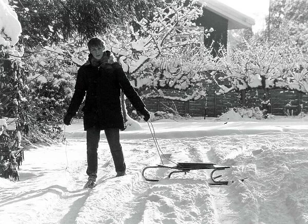 Paperboy Stephen Sales delivers his newspapers using a sledge after heavy snow in England